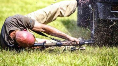 Человек стреляет из положения лёжа на боку.