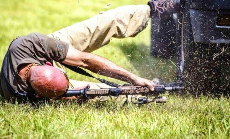 Человек стреляет из положения лёжа на боку.